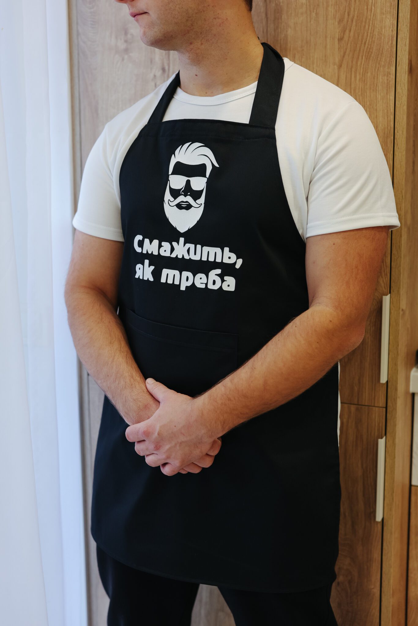 На даному зображенні представлений фартух з веселим принтом "Смажить, як треба". Фартух має чорний колір і виготовлений з якісного матеріалу. На фартушку зображено кухонні прилади, зелень та напис "Смажить, як треба". Фартух має регульовані зав'язки на шиї та поясі, що дозволяє налаштувати його під потрібний розмір. Цей фартух стане відмінним подарунком для тих, хто любить готувати та прикрашати свій дім.