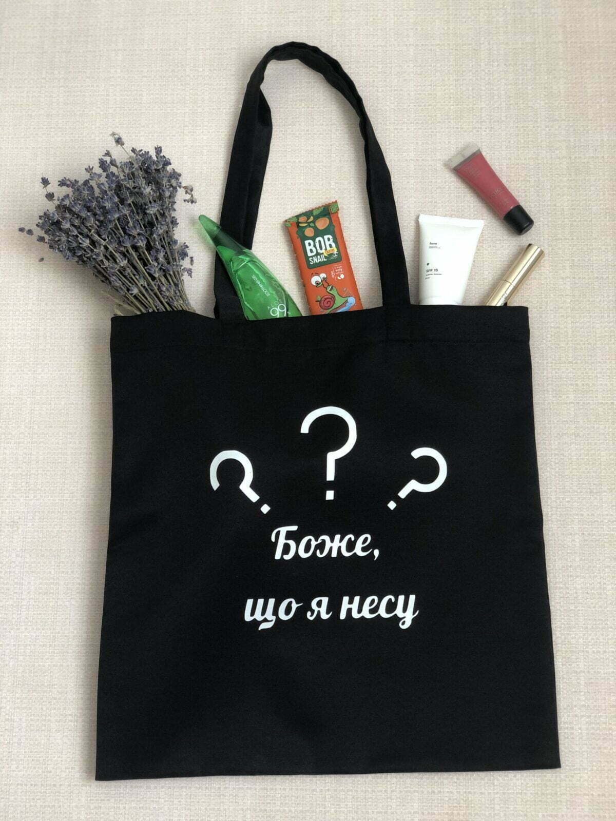 Шопер з принтом "Боже, що я несу" - стильний та практичний аксесуар. Зображення показує шопер з ексклюзивним принтом "Боже, що я несу". Ручки для носіння забезпечують зручність та комфорт, а місткий внутрішній відділ дозволяє зберігати необхідні речі під час прогулянок або походів по магазинах. Цей шопер відмінно підходить для щоденного використання та створить неповторний образ.