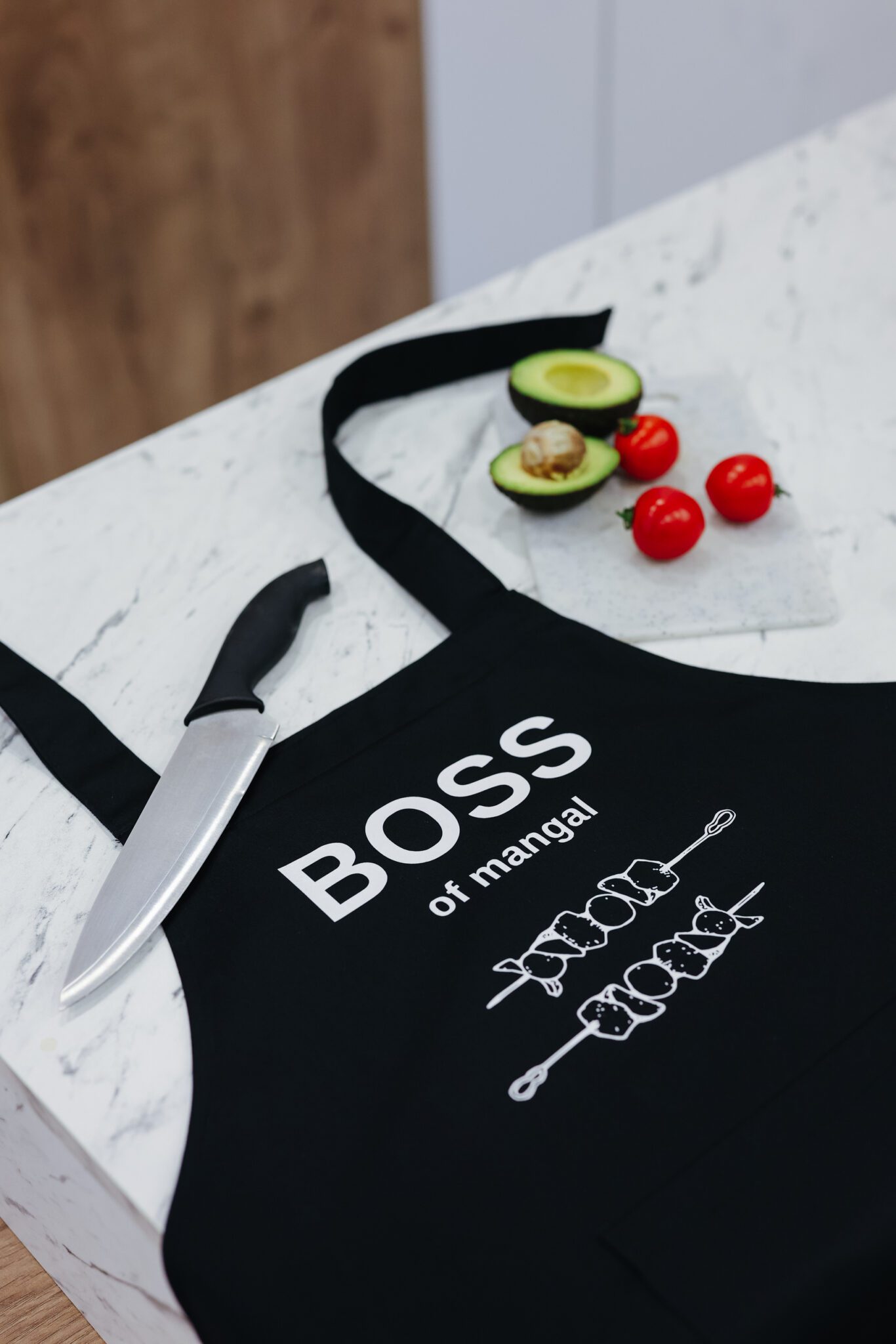 На даному зображенні представлений фартух з веселим принтом "Boss of mangal". Фартух має чорний колір і виготовлений з якісного матеріалу. На фартушку зображено кухонні прилади, зелень та напис "Boss of mangal". Фартух має регульовані зав'язки на шиї та поясі, що дозволяє налаштувати його під потрібний розмір. Цей фартух стане відмінним подарунком для тих, хто любить готувати та прикрашати свій дім.