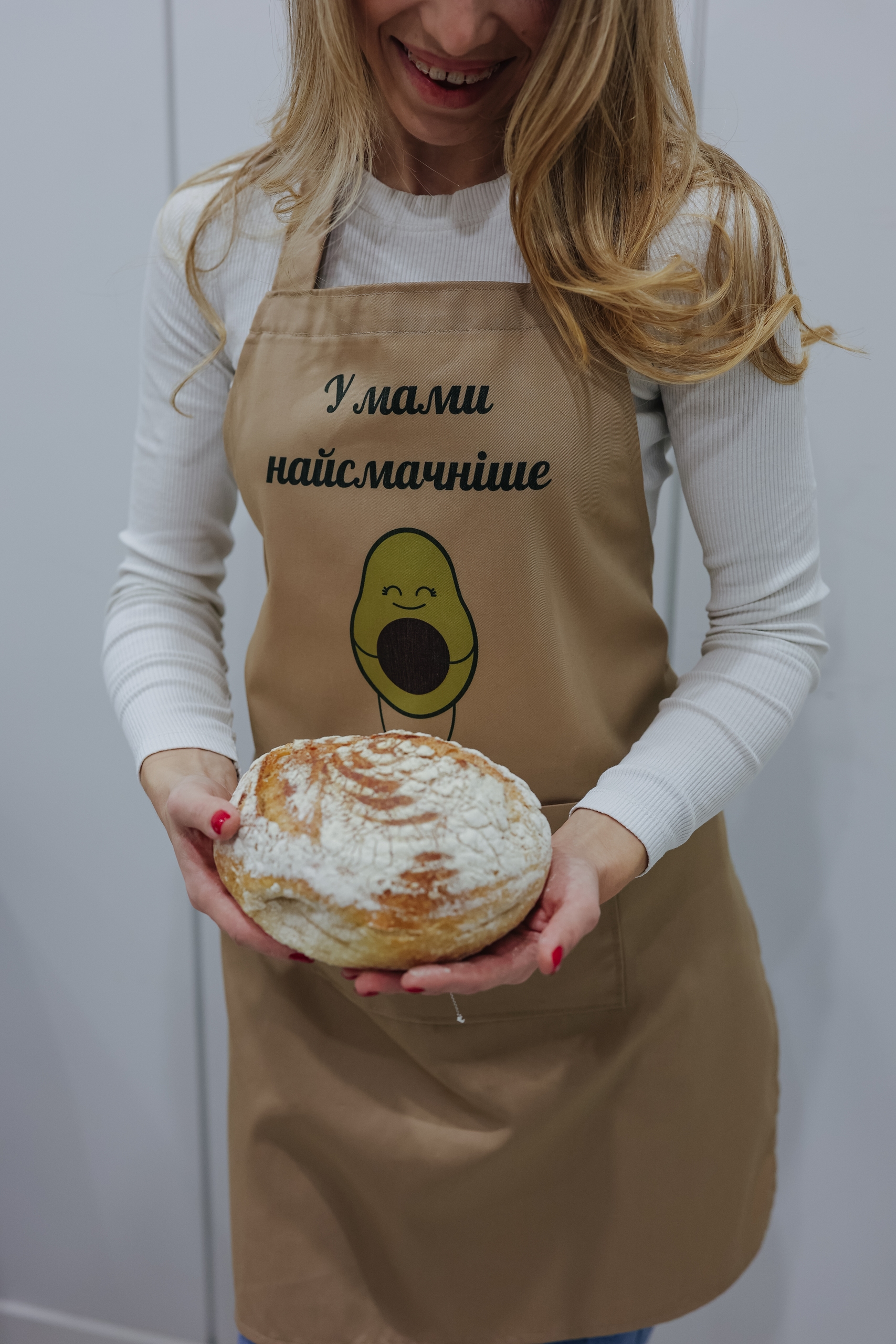 На даному зображенні представлений фартух з веселим принтом "У мами найсмачніше (Авокадо)". Фартух має бежевий колір і виготовлений з якісного матеріалу. На фартушку зображено кухонні прилади, зелень та напис "У мами найсмачніше (Авокадо)". Фартух має регульовані зав'язки на шиї та поясі, що дозволяє налаштувати його під потрібний розмір. Цей фартух стане відмінним подарунком для тих, хто любить готувати та прикрашати свій дім.