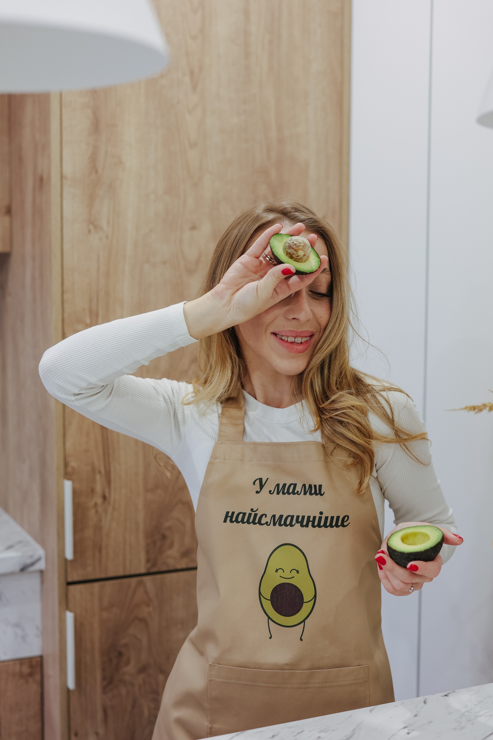 На даному зображенні представлений фартух з веселим принтом "У мами найсмачніше (Авокадо)". Фартух має бежевий колір і виготовлений з якісного матеріалу. На фартушку зображено кухонні прилади, зелень та напис "У мами найсмачніше (Авокадо)". Фартух має регульовані зав'язки на шиї та поясі, що дозволяє налаштувати його під потрібний розмір. Цей фартух стане відмінним подарунком для тих, хто любить готувати та прикрашати свій дім.